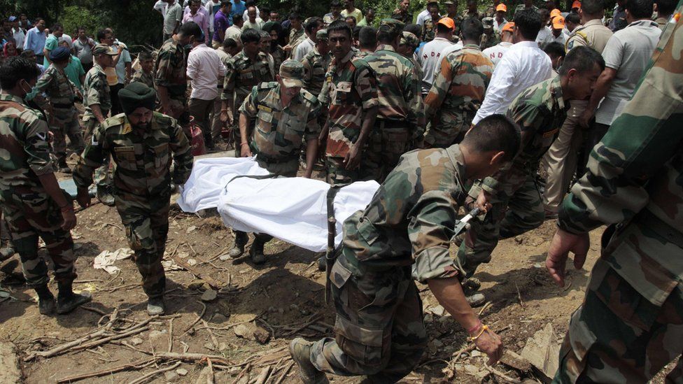 Indian army soldiers and rescue personnel look for survivors after a landslide along a highway at Kotrupi