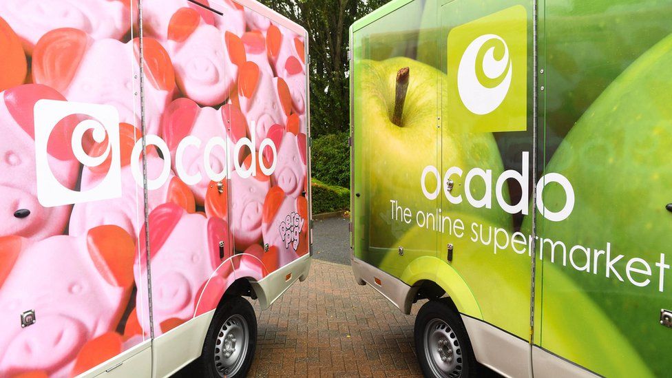 Файловая фотография фургонов доставки Ocado: тот, что слева, украшен фотографиями ярко-розовых конфет в форме свиней, тот, что справа, с зелеными яблоками