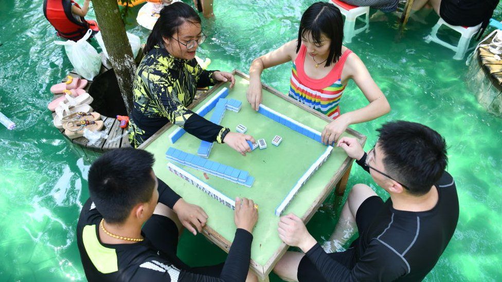 People playing the tile-based game of mahjong in water to cool down at an attraction in Sichuan.