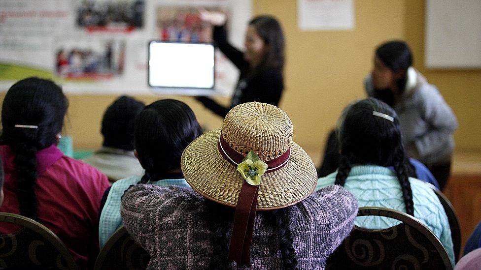 Women watch a demonstration of how the Quipu website works