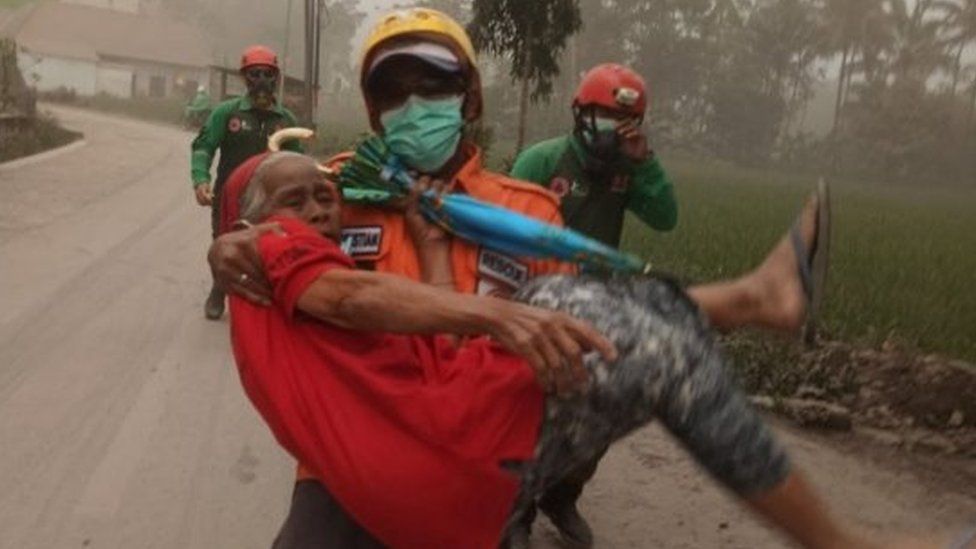 Elderly resident evacuated by a rescuer - picture supplied by BNPB