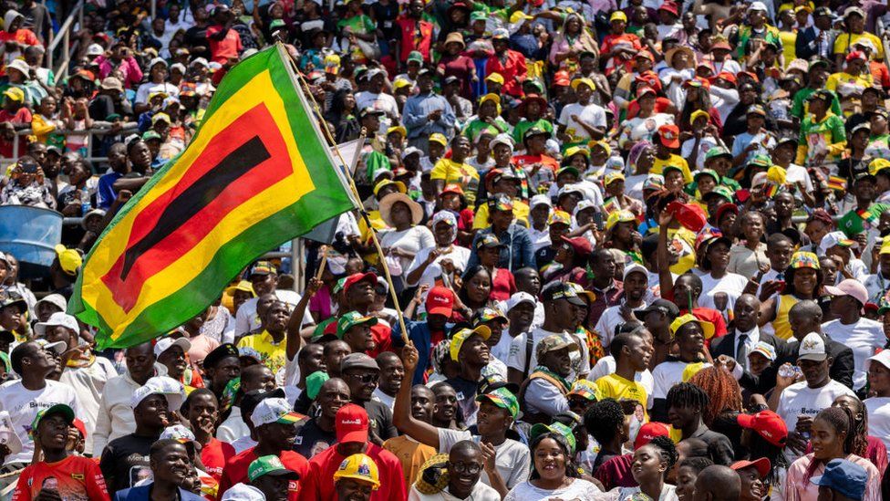 Large crowd of people holding Zimbabwe flag, 4 September