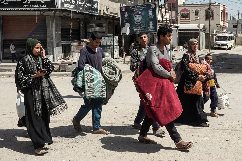 Palestinians carry belongings as people fleeing conflict leave their homes, in the Nuseirat refugee camp in central Gaza on 12 April 2024