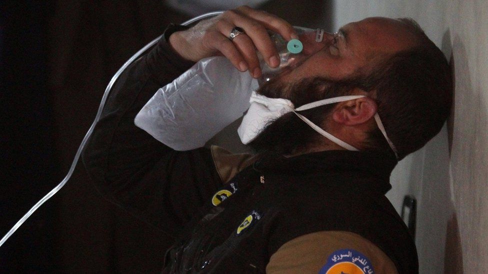 A rescue worker breathes through an oxygen mask after helping people following a suspected chemical attack in Khan Sheikhoun, Idlib province, Syria (4 April 2017)