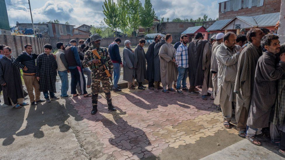 Indian paramilitary troopers stand guard as Kashmiris wait in queue to cast their votes during the second phase of Indian parliamentary-election on April 18, 2019, in Srinagar.