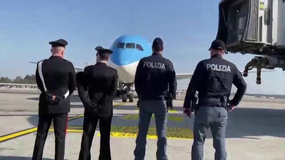 Police stand infront of a plane