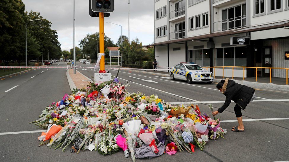 A woman places flowers at a memorial as a tribute to victims of the mosque attacks, near a police line outside Masjid Al Noor in Christchurch, New Zealand, March 16, 2019.