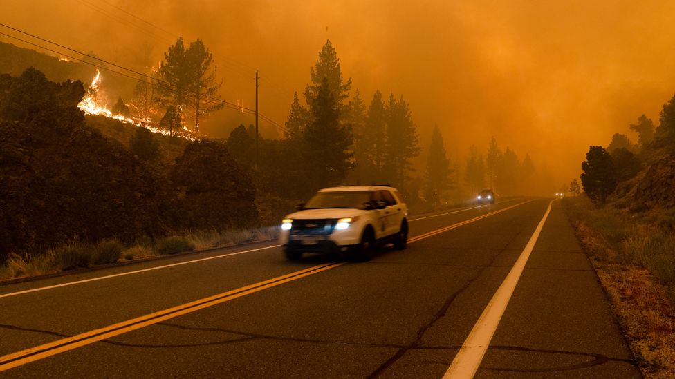Vehicles drive down Highway 89 as the Tamarack Fire fills the sky with smoke. California 17 Jul 2021