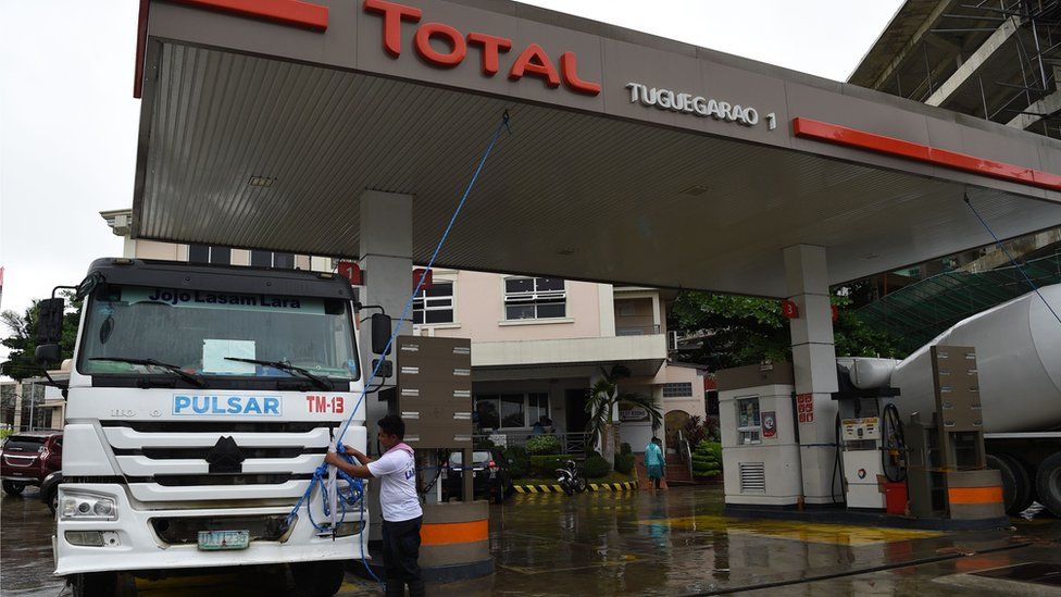 A worker anchors the roof of a fuel station to a mixer truck as Super Typhoon Mangkhut approaches the city of Tuguegarao