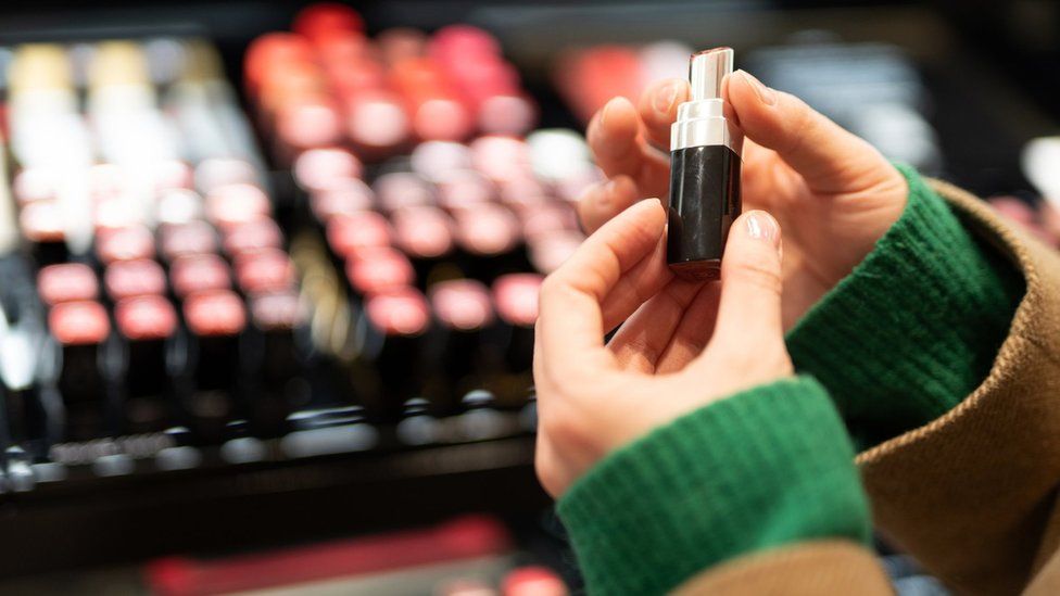 Woman holding a lipstick in a make-up store