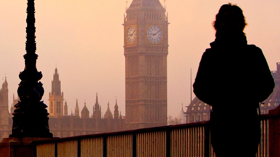 A person walks near Westminster, London, on a foggy day