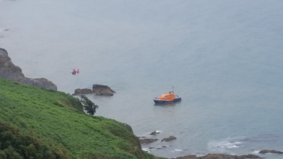 lifeboat in sea near cliff edge