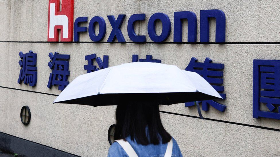 A pistillate   carrying an umbrella walks past   the Foxconn gathering  successful  Taipei.