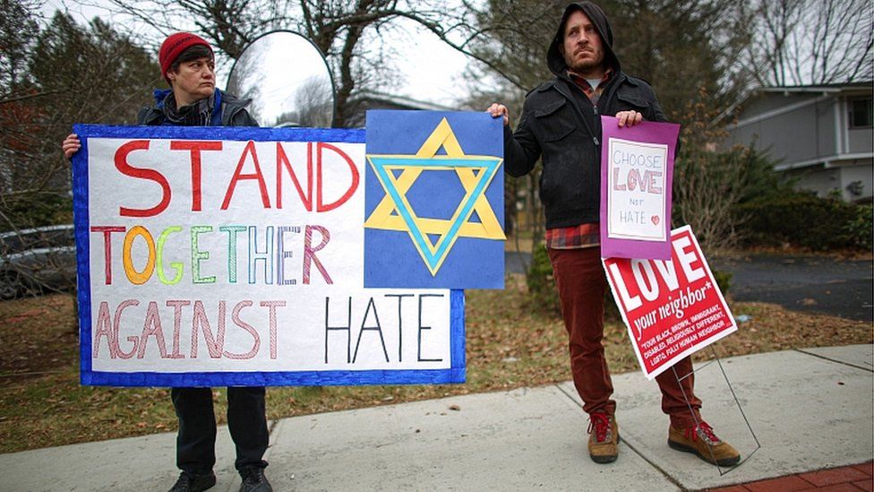 People hold signs of support near the house of Rabbi Chaim Rottenberg on December 29, 2019 in Monsey, New York