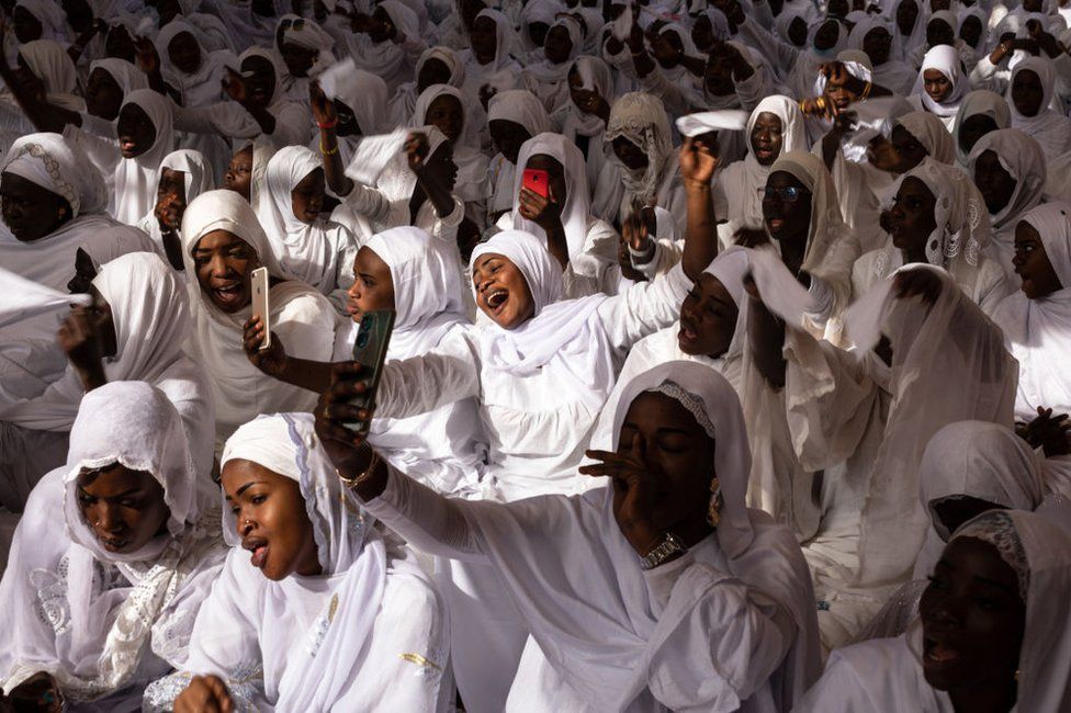 Members of the Layene Brotherhood, dressed in all white, sing and sway.