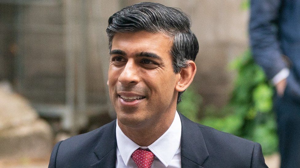 Rishi Sunak smiling as he walks down a street