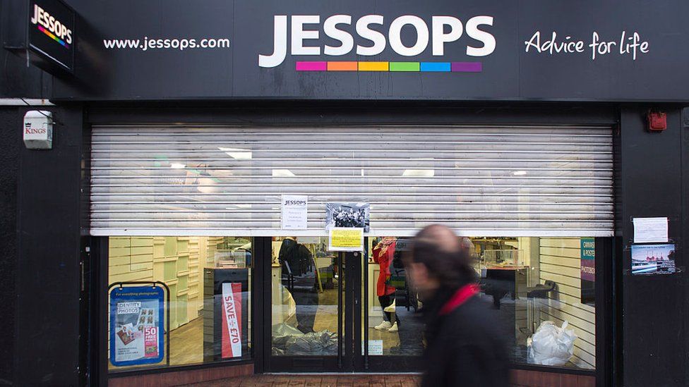 Man walks past Jessops store with shutters closed