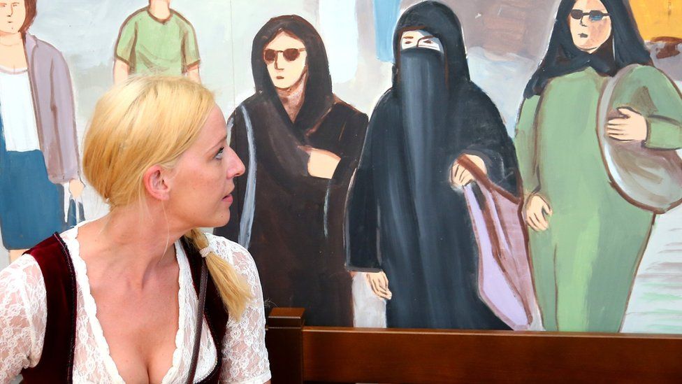 A woman studies a mural of women wearing Muslim veils at a beer tent in Munich, Bavaria, during the Oktoberfest festival on 15 September 2016