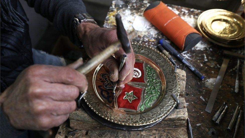 A Tunisian craftsman carves designs into a copper disk in the souk of the old city in Tunis, Tunisia.