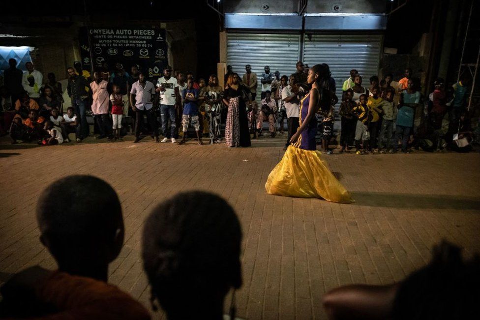 A model wearing Miss Warma designers clothes walks on the runway during a street fashion show in the popular neighbourhood of Dapoya as part of Ouaga Fashion Week 2022, in Ouagadougou, late May 14, 2022