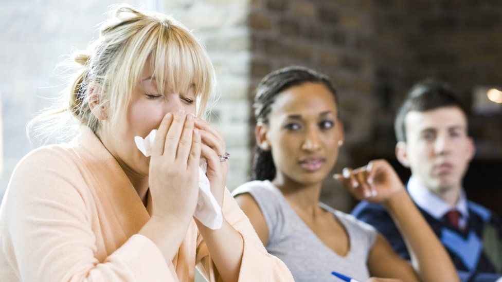 Woman sneezing during office meeting
