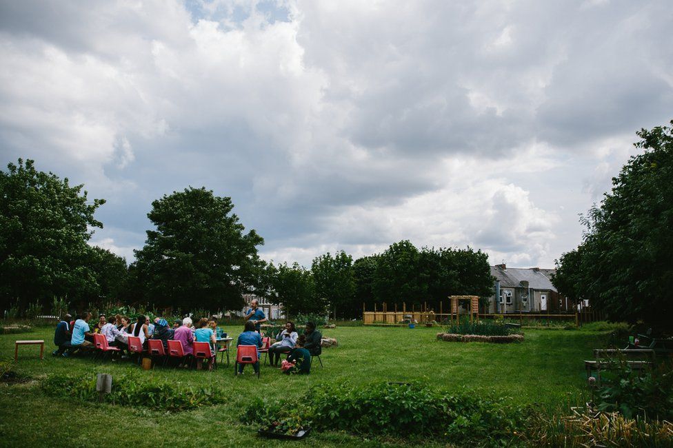 Participants and volunteers sit together for a meal at a long table