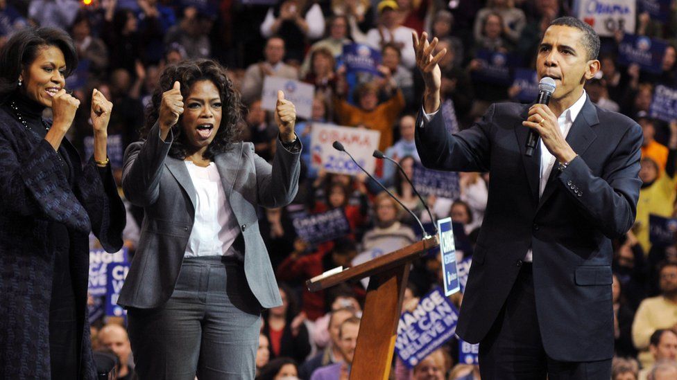 Michelle Obama (L) and Oprah Winfrey (C) listen as Barack Obama (R) addresses a crowd in Manchester, New Hampshire in 2007.