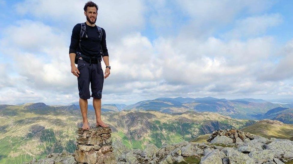 Matt Scott stands on top of a trig point in barefoot