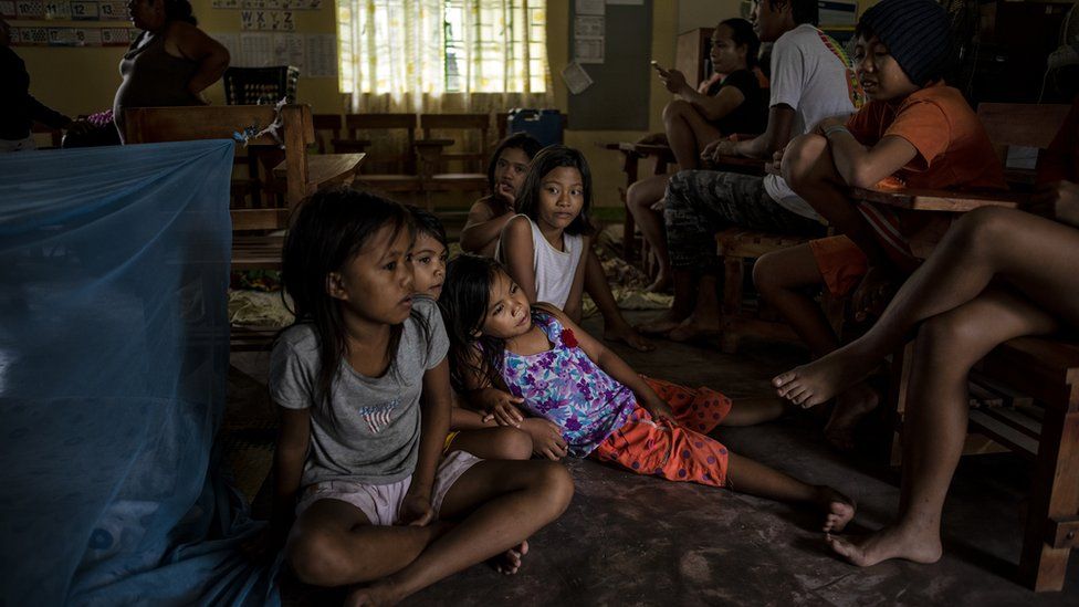 Children sitting on the floor of a classroom in Tuguegarao