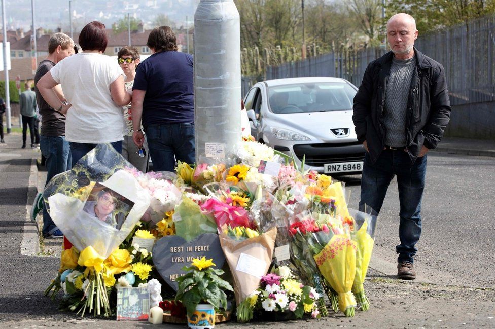 A man looks at floral tributes to Lyra McKee close to where she was shot in Londonderry
