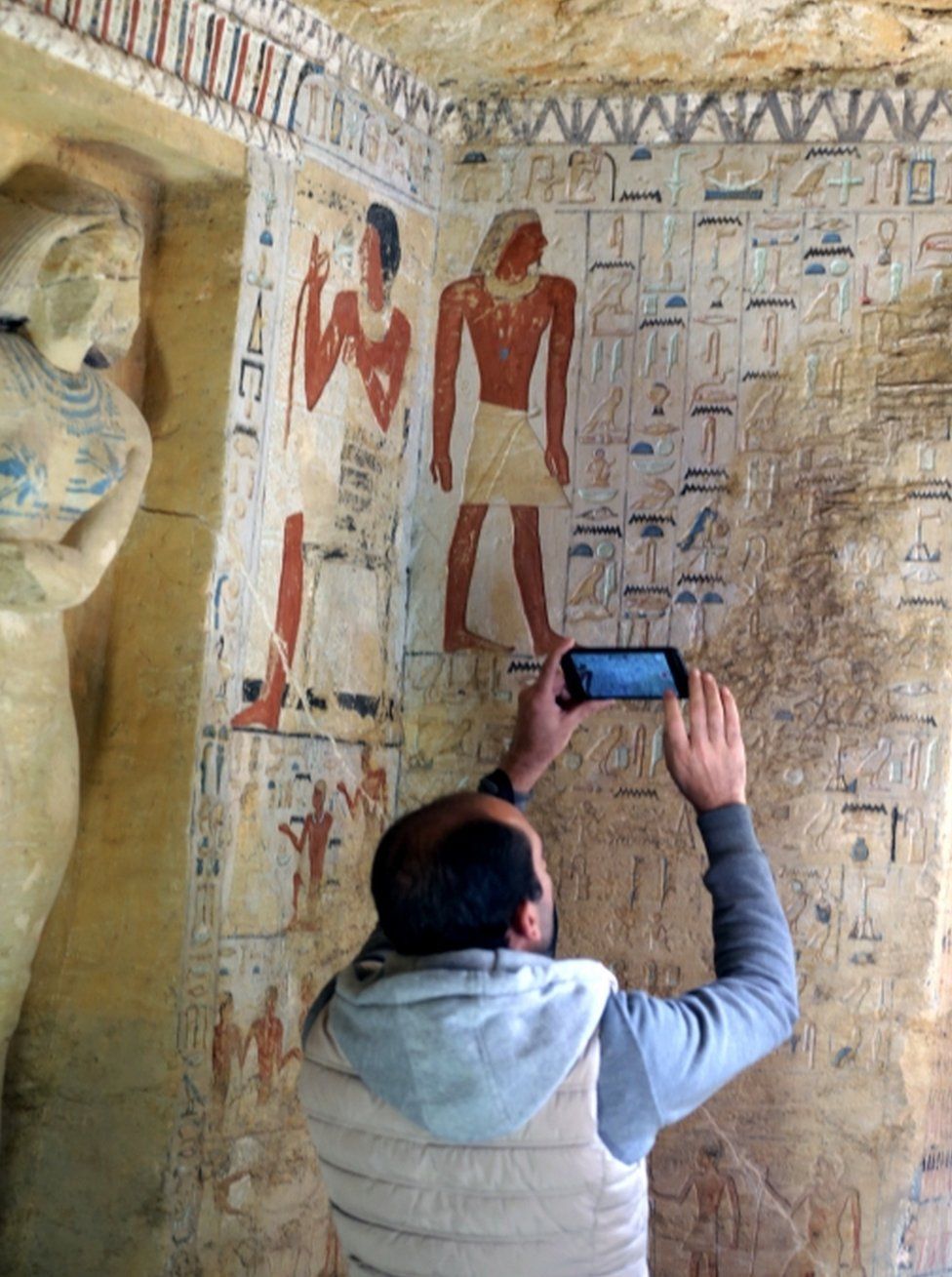 A man takes photos of the well-preserved hieroglyphs inside the newly-discovered tomb of Wahtye