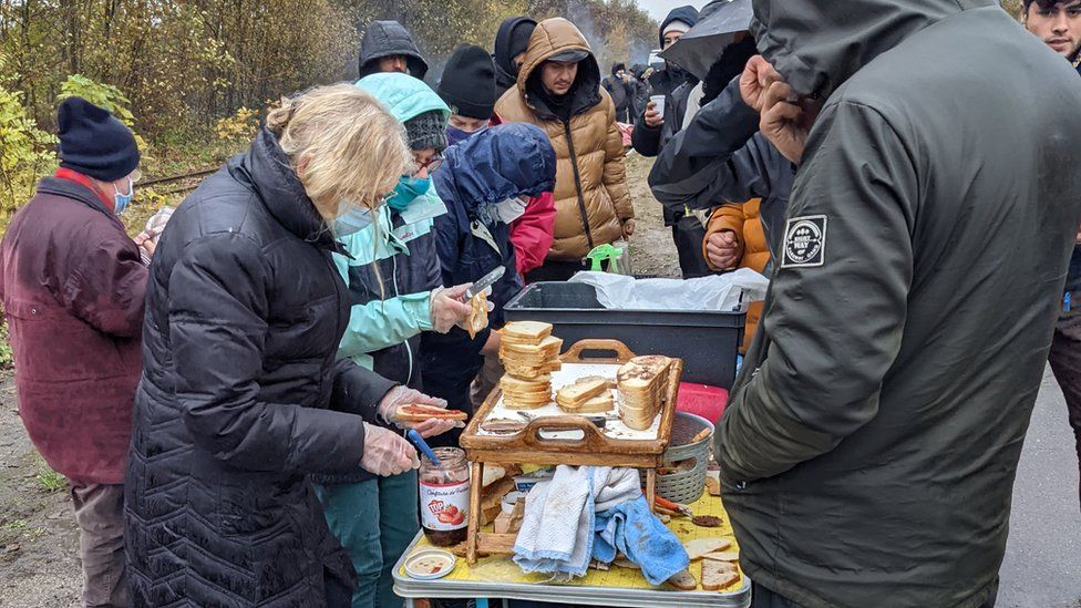 Volunteers give out sandwiches for breakfast at a migrant camp west of Dunkirk