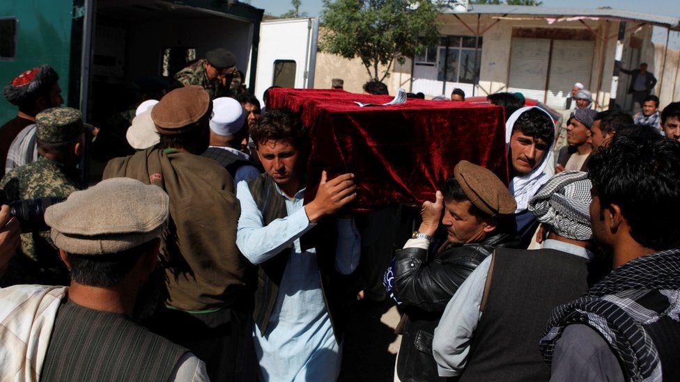 Relatives carry the body of one of the victims of a Taliban attack on an Afghan military base