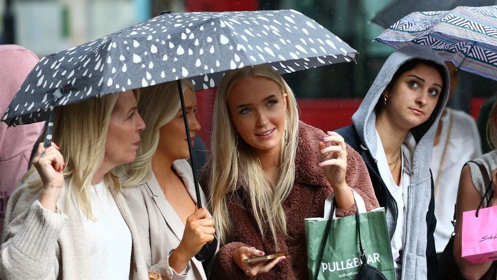 Shoppers nether  an umbrella