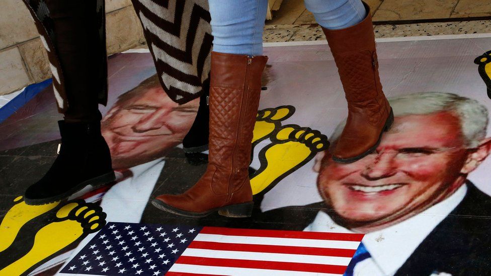 Palestinians walking on a poster of Donald Trump and Vice President Mike Pence in December
