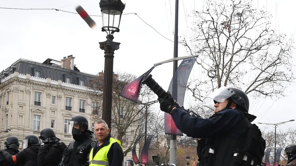 A police officer in Paris fires a tear gas canister