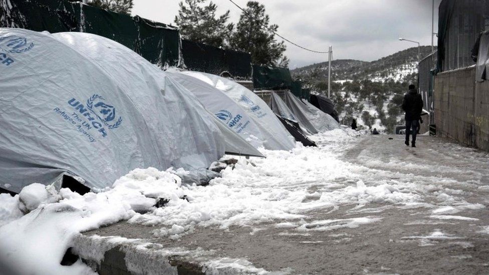 migrant walks next to snow-covered tents at the Moria hotspot on the island of Lesbos , following heavy snowfalls on January 7, 2017