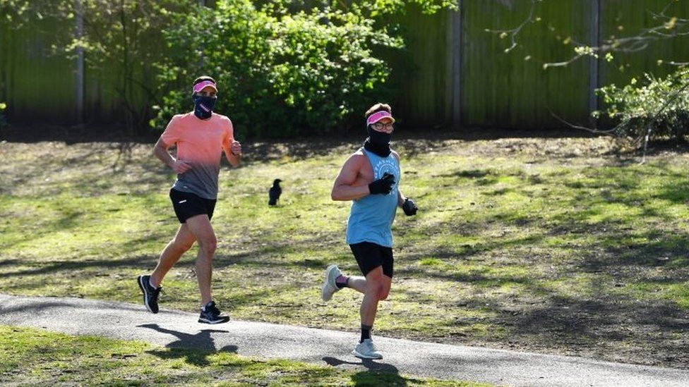 People wearing a mask run in Battersea Park on Sunday 5 April