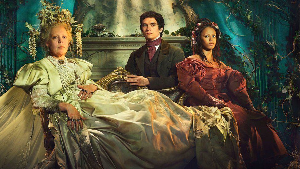 Olivia Colman as Miss Havisham in a long, pistachio-coloured gown, Fionn Whitehead as Pip in a smart suit and Shalom Brune-Franklin in a burgundy, ruched dress