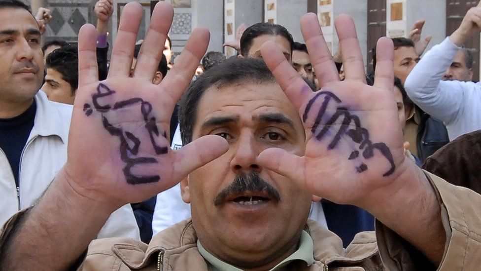 Anti-Syrian government protester, displays Arabic words on his hands, reading "Yes for freedom, no to violence" during a protest after Friday prayers in Damascus, Syria, Friday, March 25, 2011.