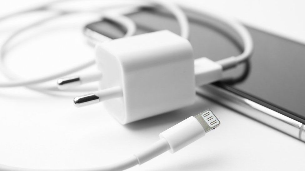 iPhone charging cable and USB power adapter lying on top of an iPhone