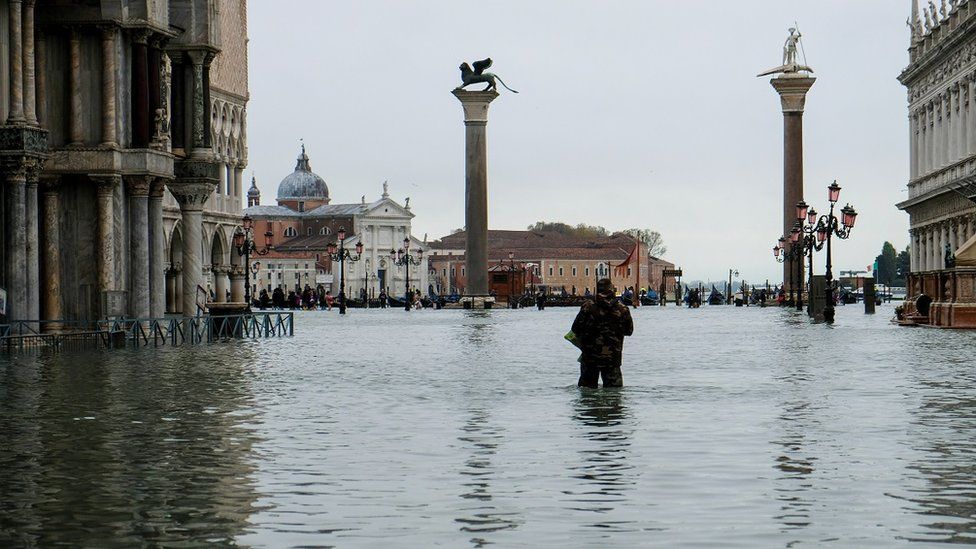 A man stands in water at the flooded St Mark"s Square