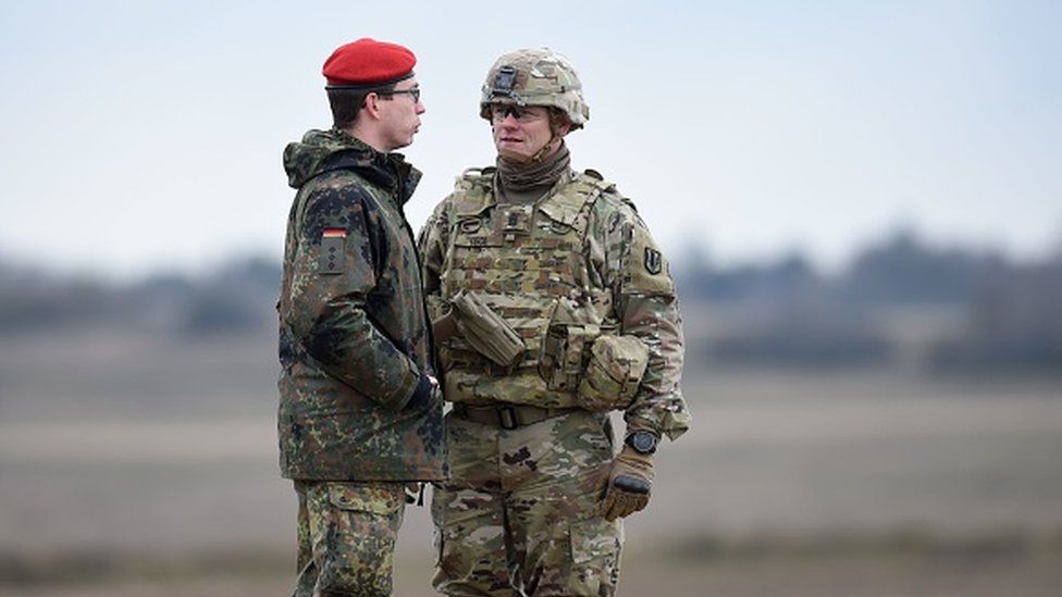 A Bundeswehr soldier (L) and an US soldier talk together during an artillery live fire event