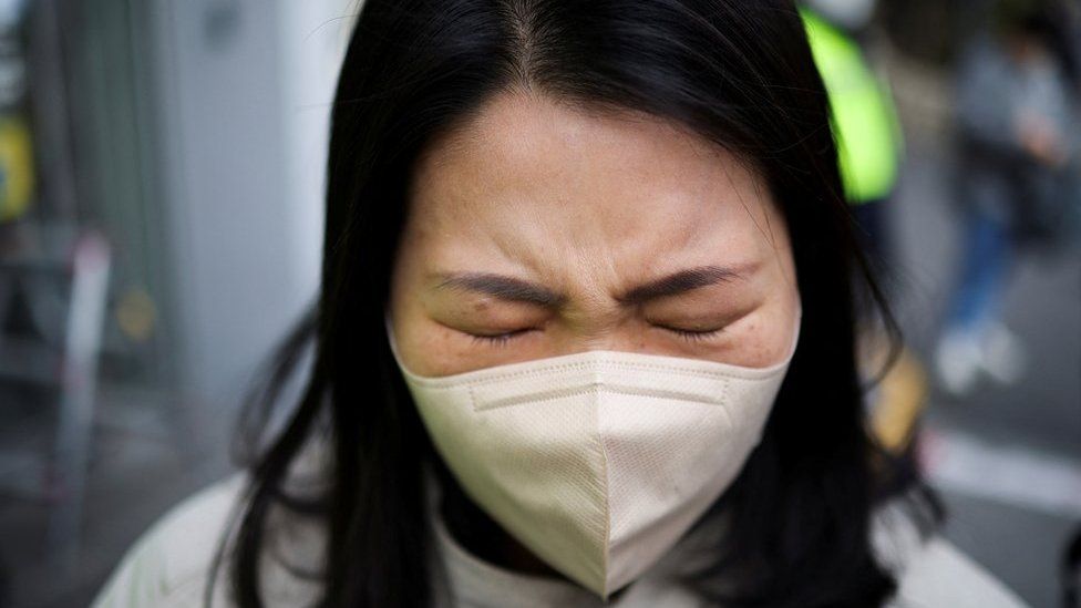 A woman mourns at a floral tribute near the scene of a crowd crush that happened during Halloween festivities, in Seoul, South Korea, November 1, 2022