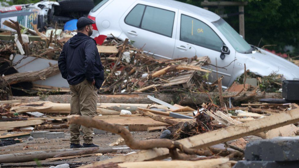 A person stands amid the debris near a damaged car after flooding in Bad Neuenahr-Ahrweiler, Germany, 16 July 2021