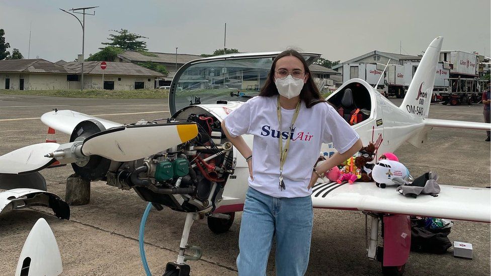Zara Rutherford in Jakarta standing in front of her aircraft which has the nose cone and cowling removed.