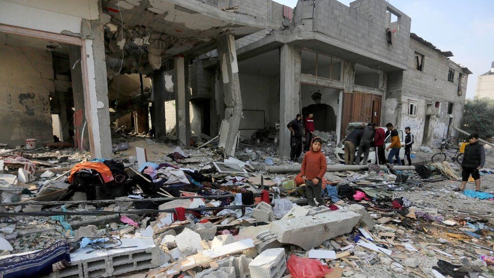 Palestinians search through the rubble of a building destroyed in a reported Israeli strike in Maghazi refugee camp, in central Gaza (28 December 2023)