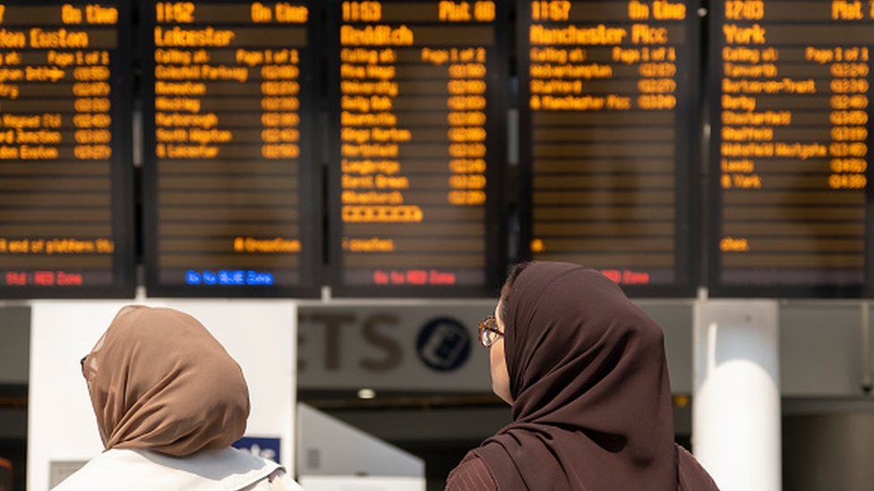 Two woman looking at a train times board