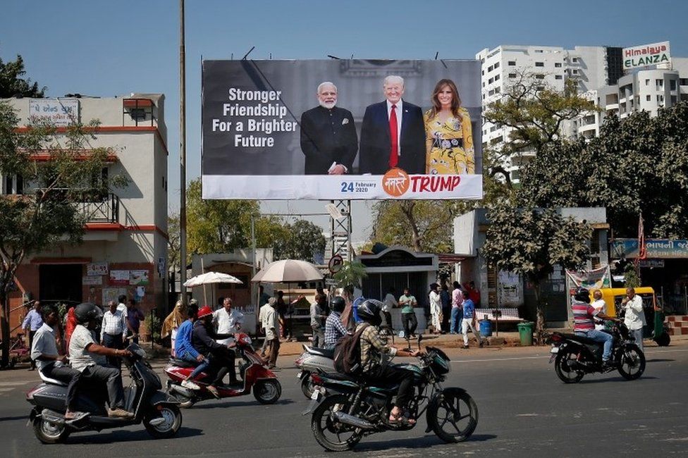People ride their motorbikes past a hoarding with the images of India"s Prime Minister Narendra Modi, U.S. President Donald Trump and first lady Melania Trump ahead of Trump"s visit, in Ahmedabad, India, February 18, 2020.