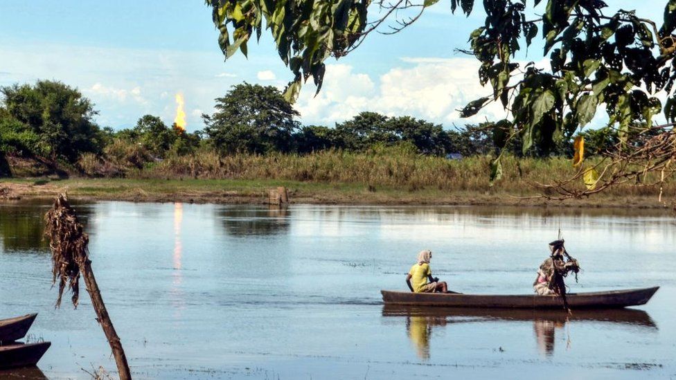 Locals navigate a boat down a river in Assam